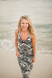 Portrait of cheerful young woman standing at beach