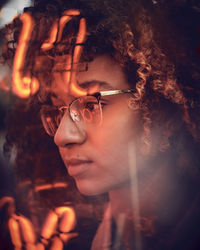 Close-up of young woman seen through window with reflection