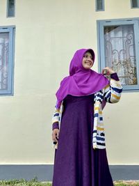 Portrait of woman standing against wall