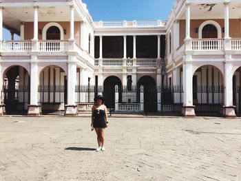 Woman standing against historic building on sunny day