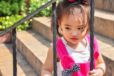 Cute girl standing against railing