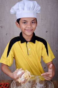 Portrait of cute boy wearing chef hat preparing food in kitchen at home