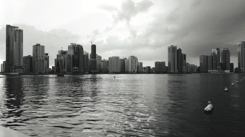 Sea by buildings against sky in city