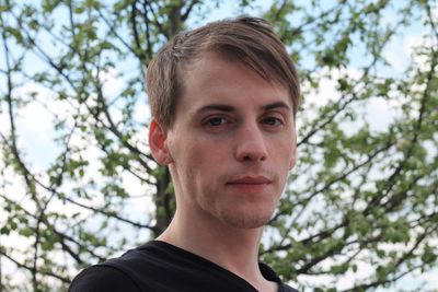 Portrait of young man against trees