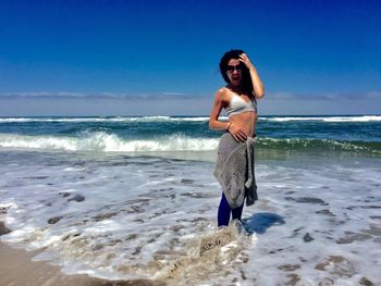 Portrait of young woman standing on shore at beach