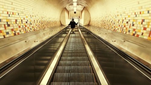 Rear view of man traveling on illuminated escalator