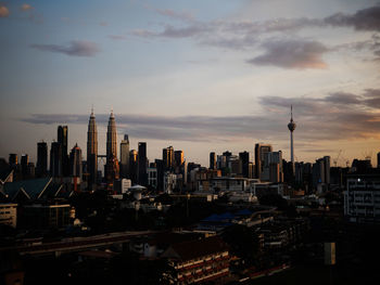 Modern buildings in city against sky during sunset
