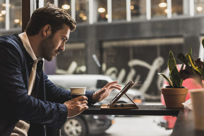 Usa, new york city, businessman sitting in coffee shop, using digital tablet