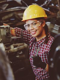 Portrait of smiling young woman holding tool at industry