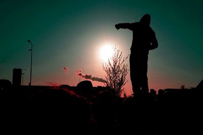 Silhouette of people on field at sunset