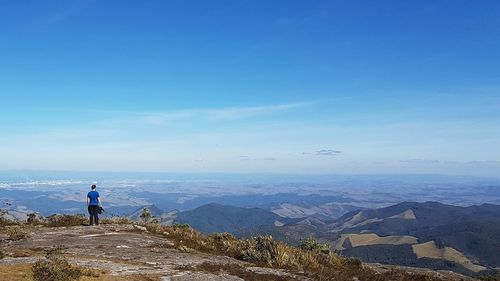 Man standing on mountain against blue sky