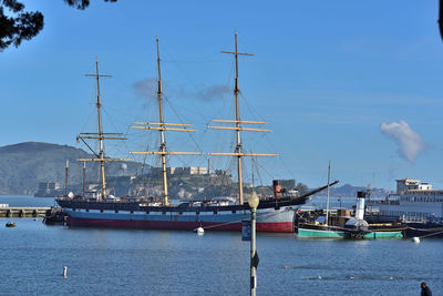 Sailboats moored in sea against blue sky