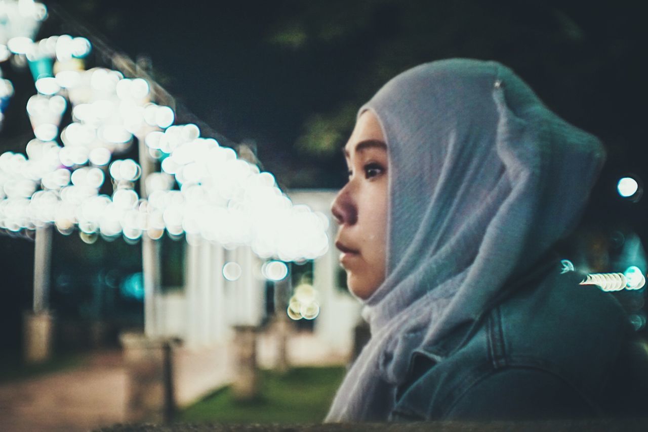 headshot, young adult, portrait, one person, real people, lifestyles, young men, looking away, leisure activity, looking, night, smoke - physical structure, focus on foreground, illuminated, warning sign, social issues, casual clothing, risk, contemplation, hood - clothing