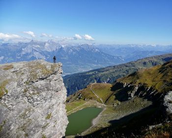 Distant view of person standing on cliff against sky