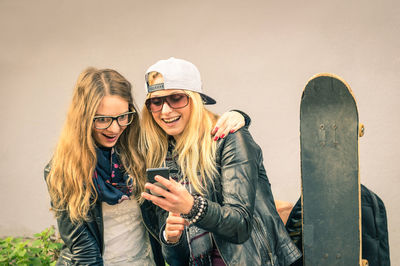 Portrait of smiling young woman standing on smart phone