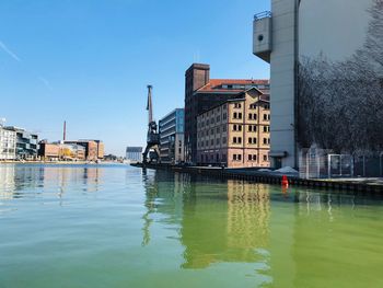 Buildings by river against sky in city