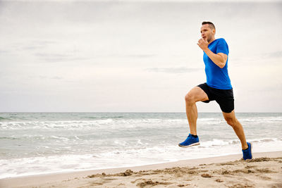 Full length of man enjoying at beach against sky