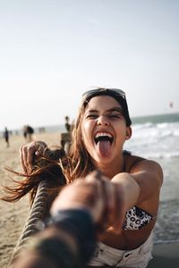 Portrait of young woman holding camera at beach