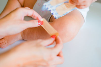 Cropped hands of woman applying band aid on baby leg