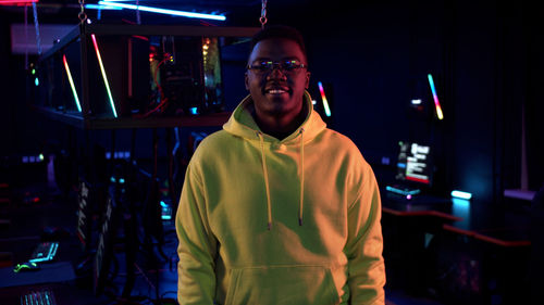 Portrait of young man standing in internet cafe