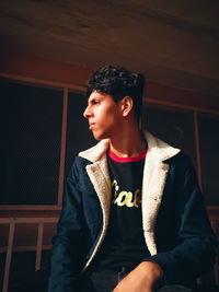 Young man looking away while sitting on seat at home