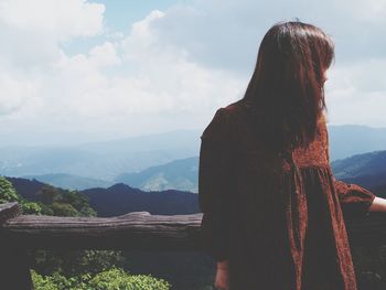 Rear view of woman looking at mountain range against sky