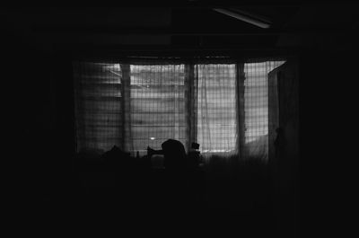 Silhouette man standing against window in building