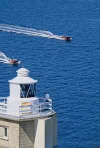 High angle view of speedboat sailing in sea by lighthouse