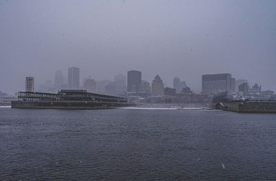 City buildings by sea against sky