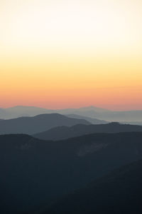 Scenic view of silhouette mountains against orange sky