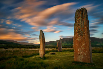 Wooden posts on field against sky during sunset