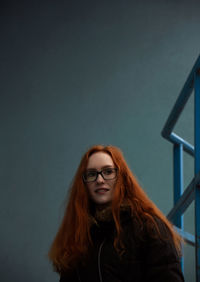 Beautiful smiling young woman standing against wall