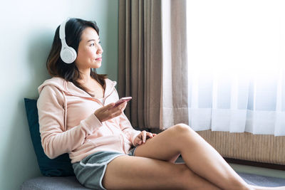 Young woman sitting on bed at home