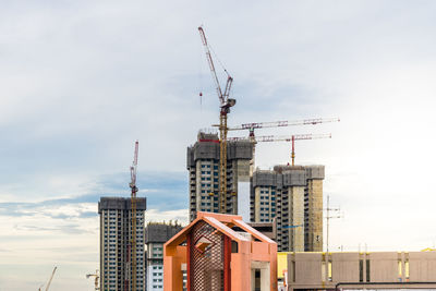 Low angle view of crane at construction site against sky