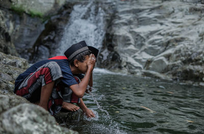 Two children enjoying the refreshing clear river water at the foot of the mountains