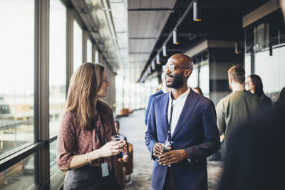 Female entrepreneur talking male coworkers in corridor at workplace