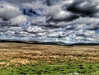 Scenic view of field against cloudy sky