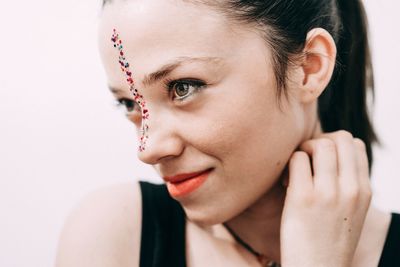 Close-up of young woman wearing make-up against wall