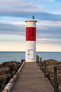 Lighthouse by sea against sky