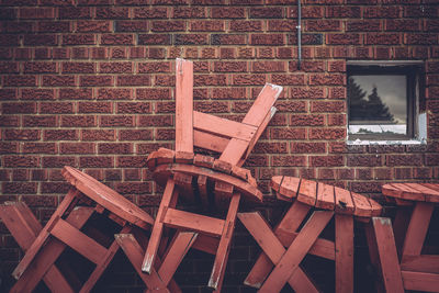 Stack of wooden tables against brick wall