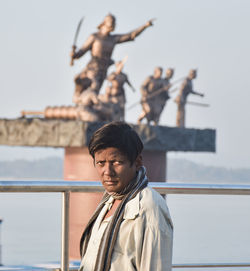 Portrait of young man standing against railing