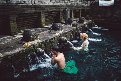 High angle view of shirtless man sitting in water