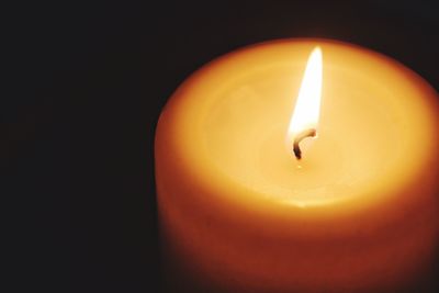 Close-up of illuminated candle against black background
