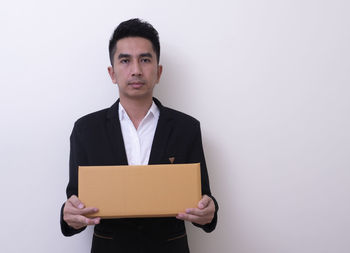 Portrait of young man standing against white background