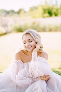 Smiling woman with eyes closed sitting outdoors