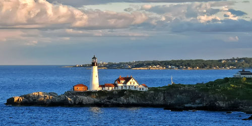 Lighthouse by sea against sky