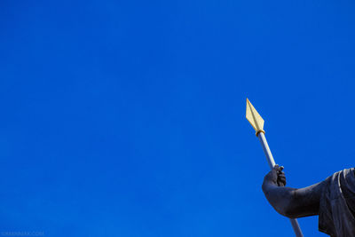 Low angle view of man hand against blue sky