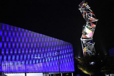 Low angle view of illuminated ferris wheel against blue sky