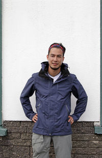 Young man in outdoor wear in front of white wall