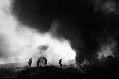 Silhouette people by smoke emitting at volcanic landscape